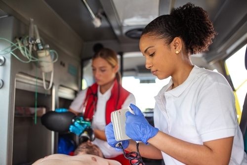 EMS Paramedics Treating Auto Accident Victim Tupelo Mississippi two paramedics treating patient inside ambulance with medical defibrillator equipment