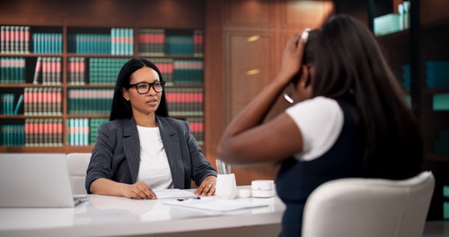 attorney in glasses listening attentively to distressed client across office desk