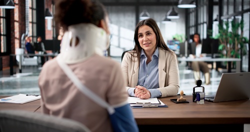 Injured Pedestrian Meeting Delivery Truck Accident Lawyer Trenton injured woman wearing neck brace meeting with professional attorney at desk