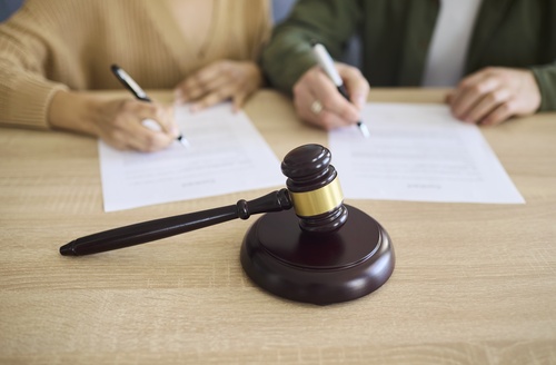 Parents Signing Joint Managing Conservatorship Agreement Houston Texas two people signing legal documents at table with judge gavel in foreground
