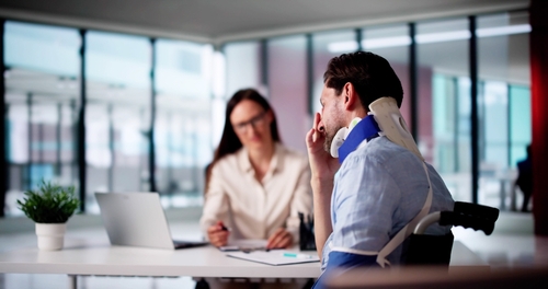 Illinois Truck Accident Injury Victim Meeting With Attorney injured worker wearing neck brace meeting with professional at office desk