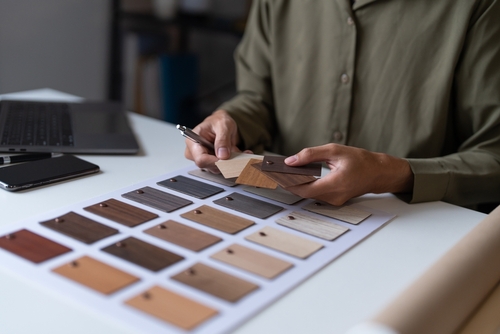 Interior Designer Reviewing Kitchen Cabinet Samples Naperville designer holding wood material swatches at desk with laptop nearby