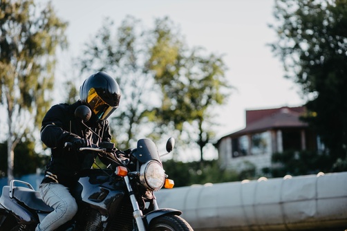male motorcyclist wearing full-face helmet seated on motorcycle outdoors