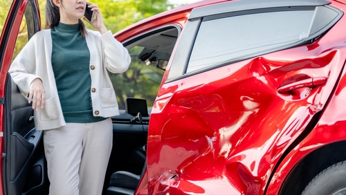 Hollywood Florida Car Accident Victim Calling Attorney After Crash woman on phone standing beside car with severe collision damage