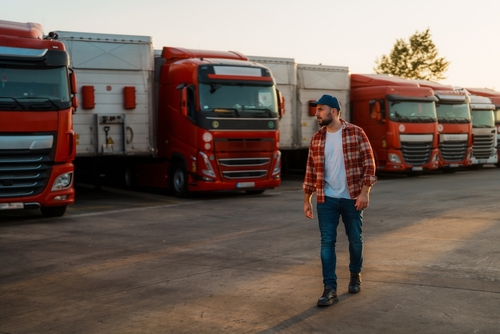 Philadelphia Commercial Fleet Owner Walking Among Company Trucks man in flannel shirt and cap walking in front of parked commercial trucks