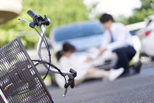fallen bicycle with basket on road after car collision with injured person