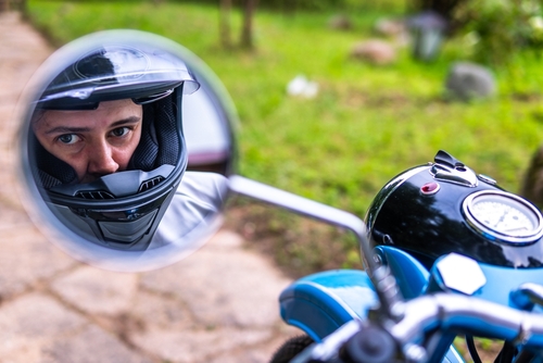 Florida Motorcyclist Helmet Reflection Rearview Mirror motorcyclist wearing helmet reflected in motorcycle side mirror outdoors