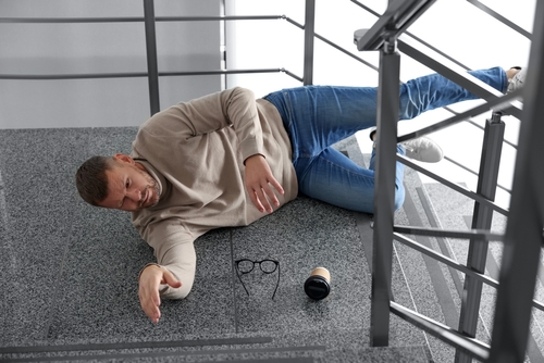 Injured Man After Slip and Fall on Miami Stairs man lying on stairs landing after fall with glasses and cup on floor