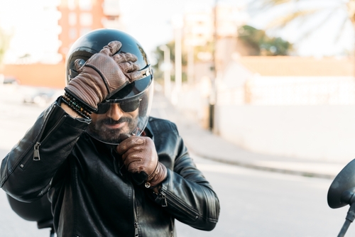 Illinois Motorcyclist Putting On Helmet Before Riding bearded motorcyclist wearing leather gloves adjusting helmet outdoors near motorcycle