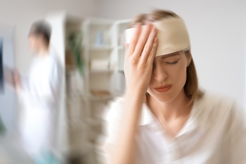 Traumatic Brain Injury After Dayton Car Accident woman with bandaged head holding hand to forehead in medical setting