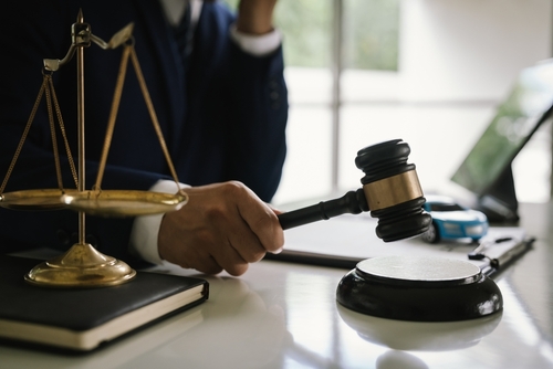 Morgantown Car Accident Attorney Gavel and Justice Scales judge striking gavel on sound block beside scales of justice on desk