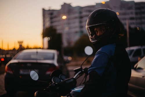 female motorcyclist wearing full-face helmet riding motorcycle in city traffic