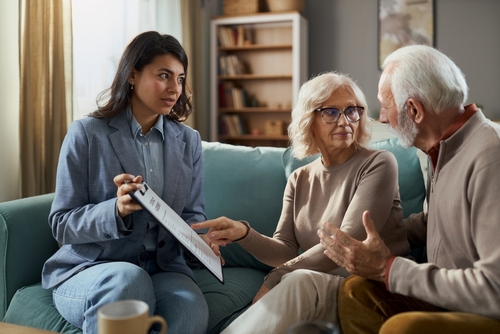 Brooklyn Probate Attorney Consulting Senior Couple on Executor Duties female attorney holding clipboard consulting with senior couple seated on sofa