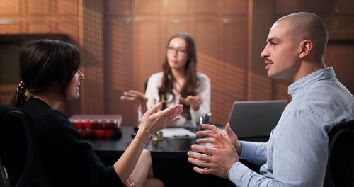 mediator facilitating discussion between two clients at office conference table