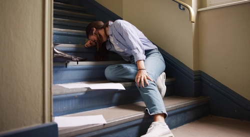 woman fallen on indoor staircase with scattered papers on steps