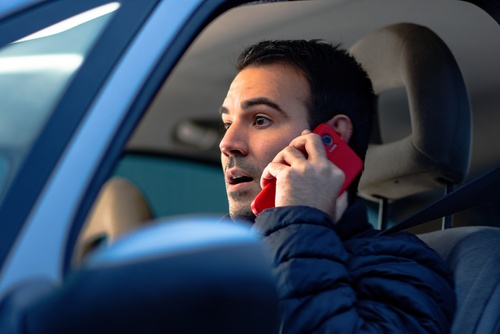distracted male driver talking on cell phone while operating vehicle