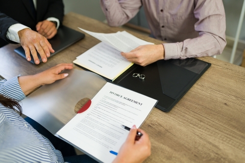 Rock Hill Couple Signing Divorce Agreement With Attorney couple signing divorce agreement document with wedding rings on table