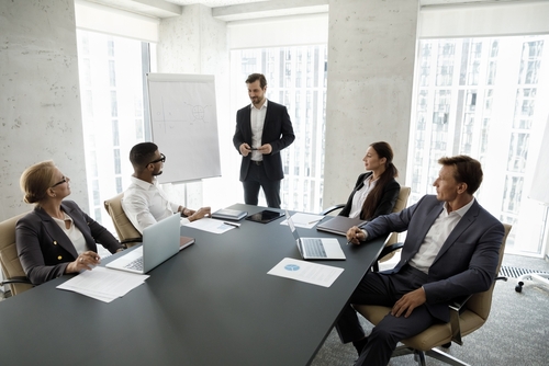 USA Stockholder Fraud Claim Corporate Meeting With Lawyer business leader standing presenting to seated colleagues around conference room table
