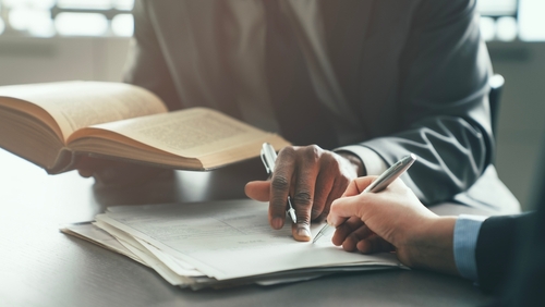 Newton Square Securities Attorney Reviewing PA Legal Documents two professionals reviewing legal documents and open law book at desk