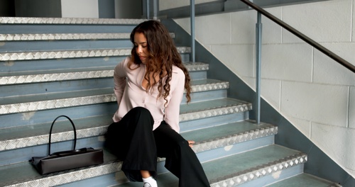 Woman Injured After Slip and Fall on Stairs Carrollton GA woman sitting on metal staircase steps with handbag beside her