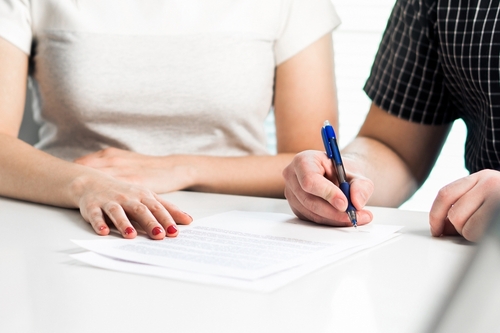 Couple Signing 401k Divorce Agreement Brooklyn two people signing legal document on table during formal agreement