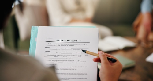 Houston Prenup Attorney Reviewing Texas Community Property Agreement person holding pen over printed Divorce Agreement legal document