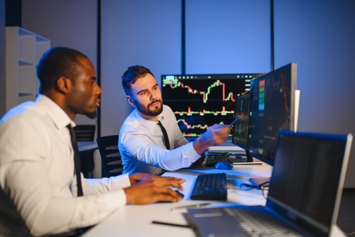 Newton Square Investors Reviewing Stockholder Fraud Claim PA two stockbrokers reviewing financial trading charts on multiple monitors together
