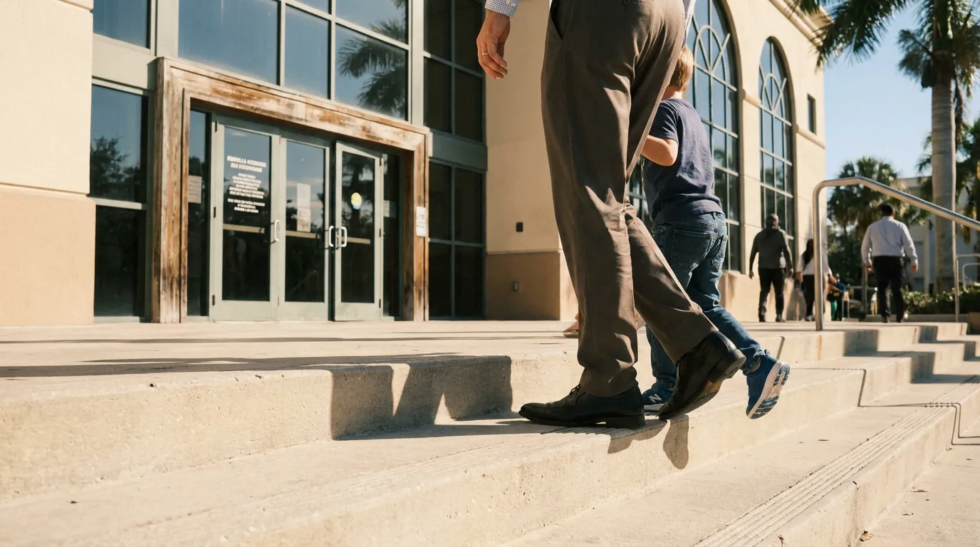 adult and child walking up courthouse steps toward glass entrance doors