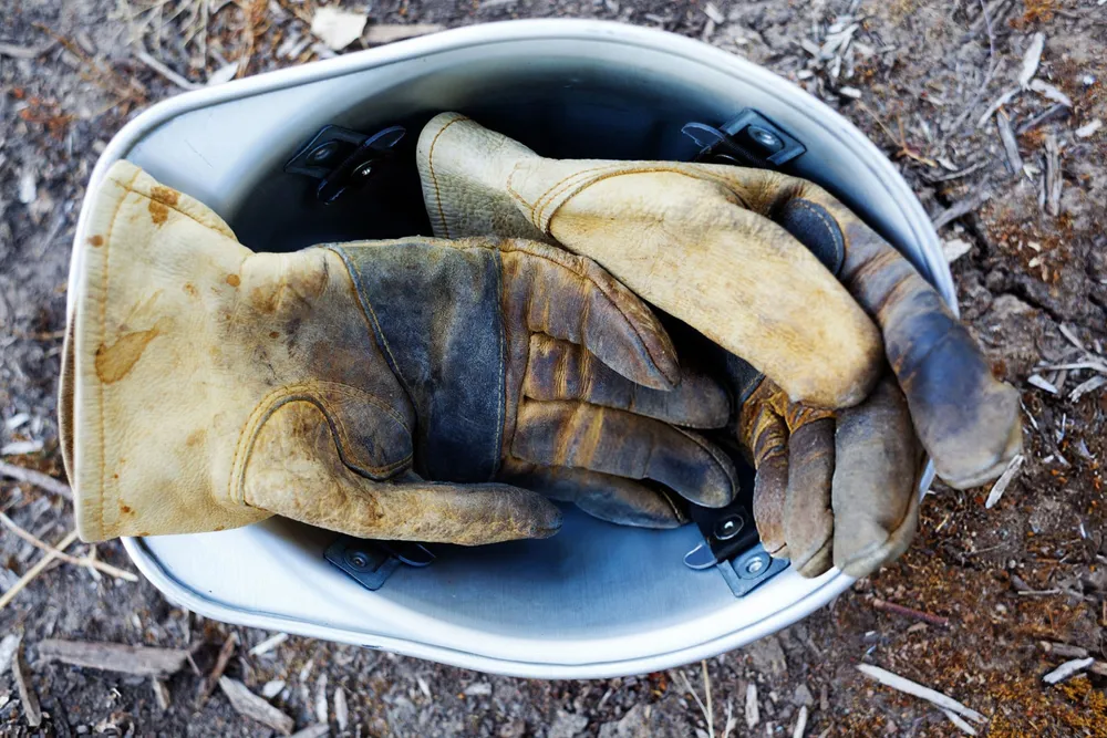 Worn Gloves Hard Hat Permian Basin Oilfield Worn leather work gloves resting inside hard hat on job site