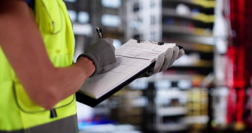 Construction worker holding a clipboard and writing on a piece of paper